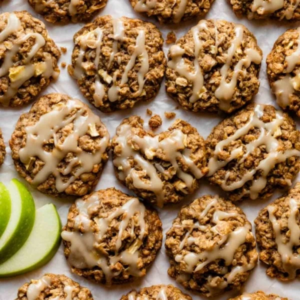 a tray of oatmeal and apple cookies with frosting drizzled on top of them