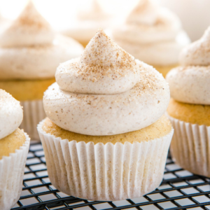 cupcakes with a swirl of frosting sitting on a dark wire rack