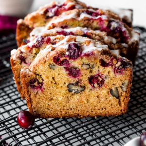 a loaf loaded with nuts and cranberries on a dark wire rack